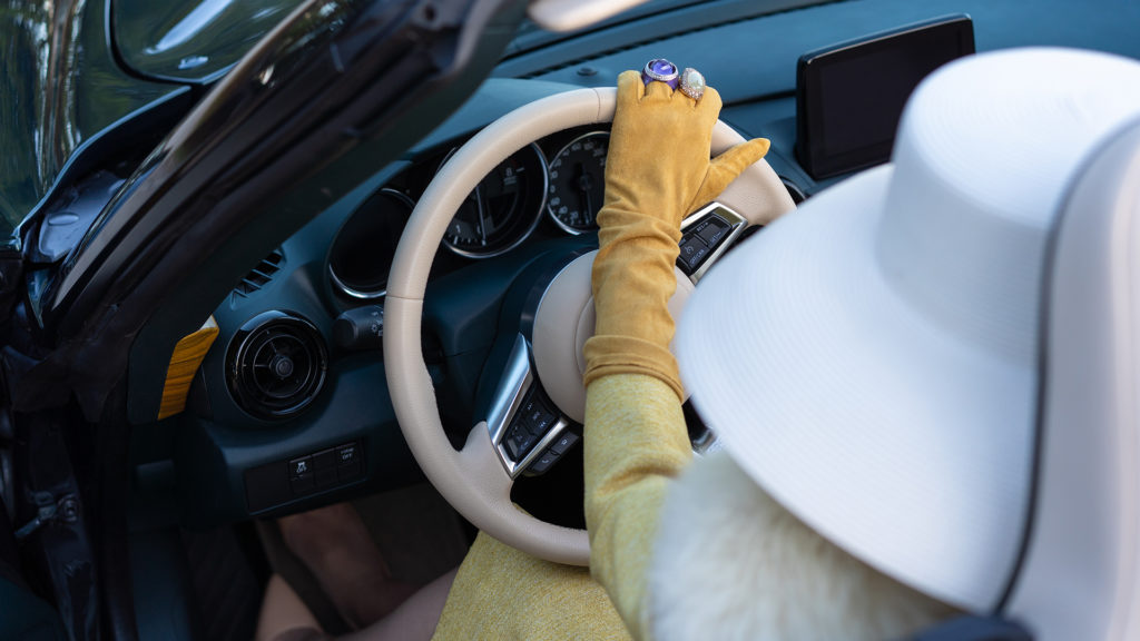 Cándidas Couture al volante del Hurtan Grand Albaycín de VeryVip Cars con un vestido amarillo, guantes enjoyados a juego y un sombrero blanco. 